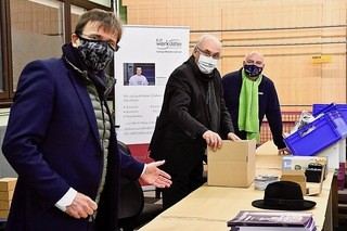 Diözesenbischof Dr. Rudolf Voderholzer (Mitte) packte gemeinsam mit KJF-Direktor Michael Eibl (vorne) und Armin Wolf (hinten) kräftig an, um das Team der Straubinger Werkstätten St. Josef beim Bestücken der Packerl fürs Weihnachtssingen #Dahoam zu unterstützen